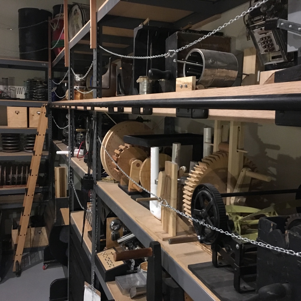 Shelving holding wooden mechanical soundmaking contraptions.