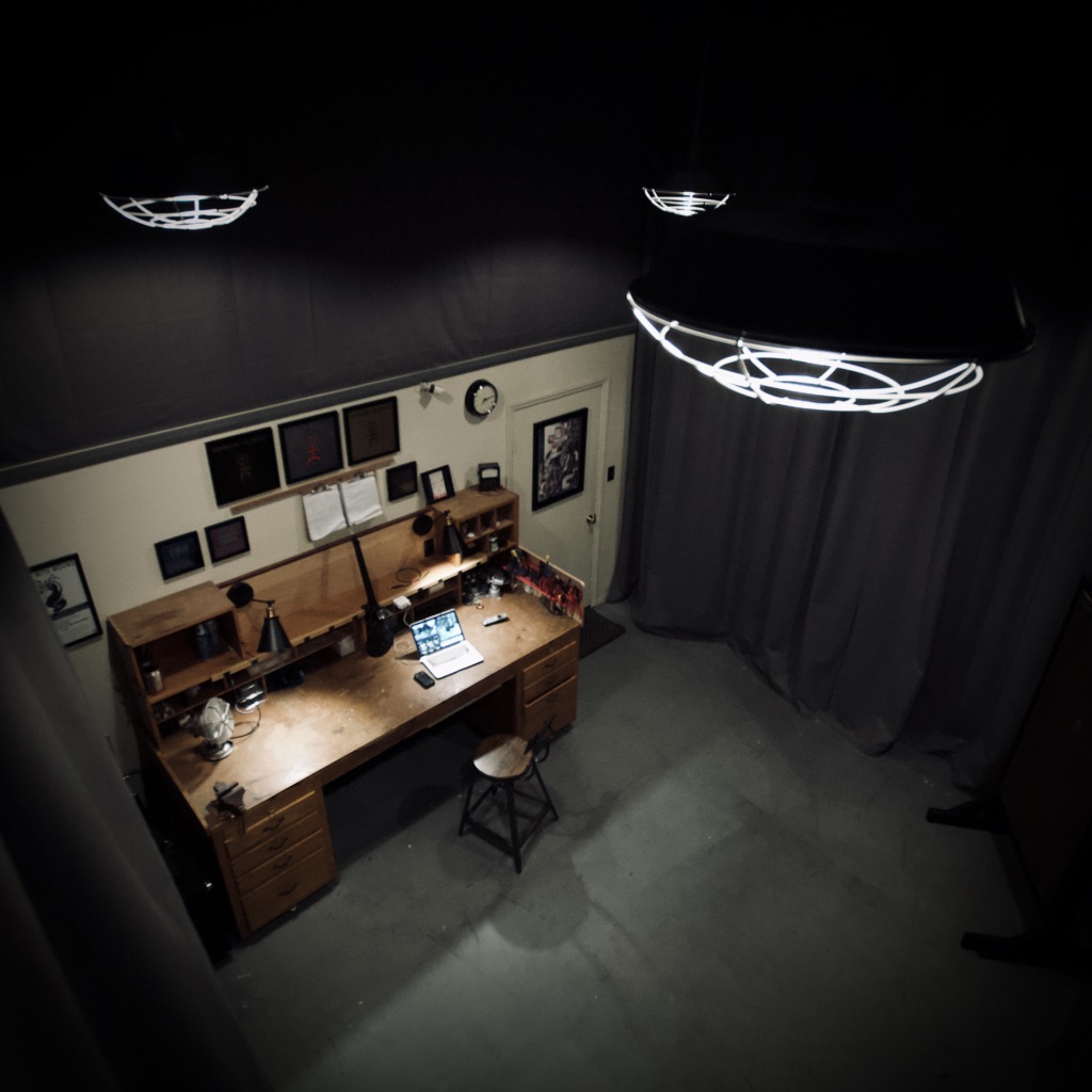 Overhead view of a workbench with tools and a computer in a curtained room.