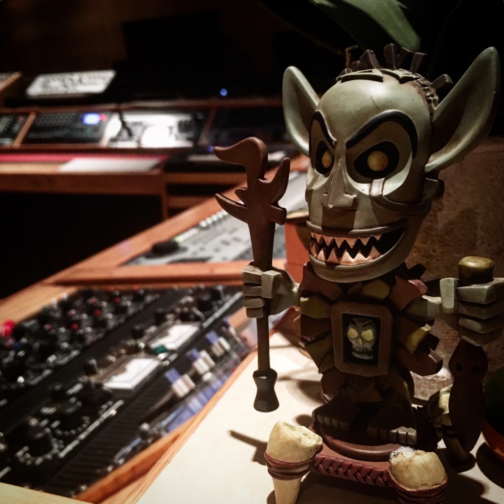 Small figurine placed on a studio mixing console.