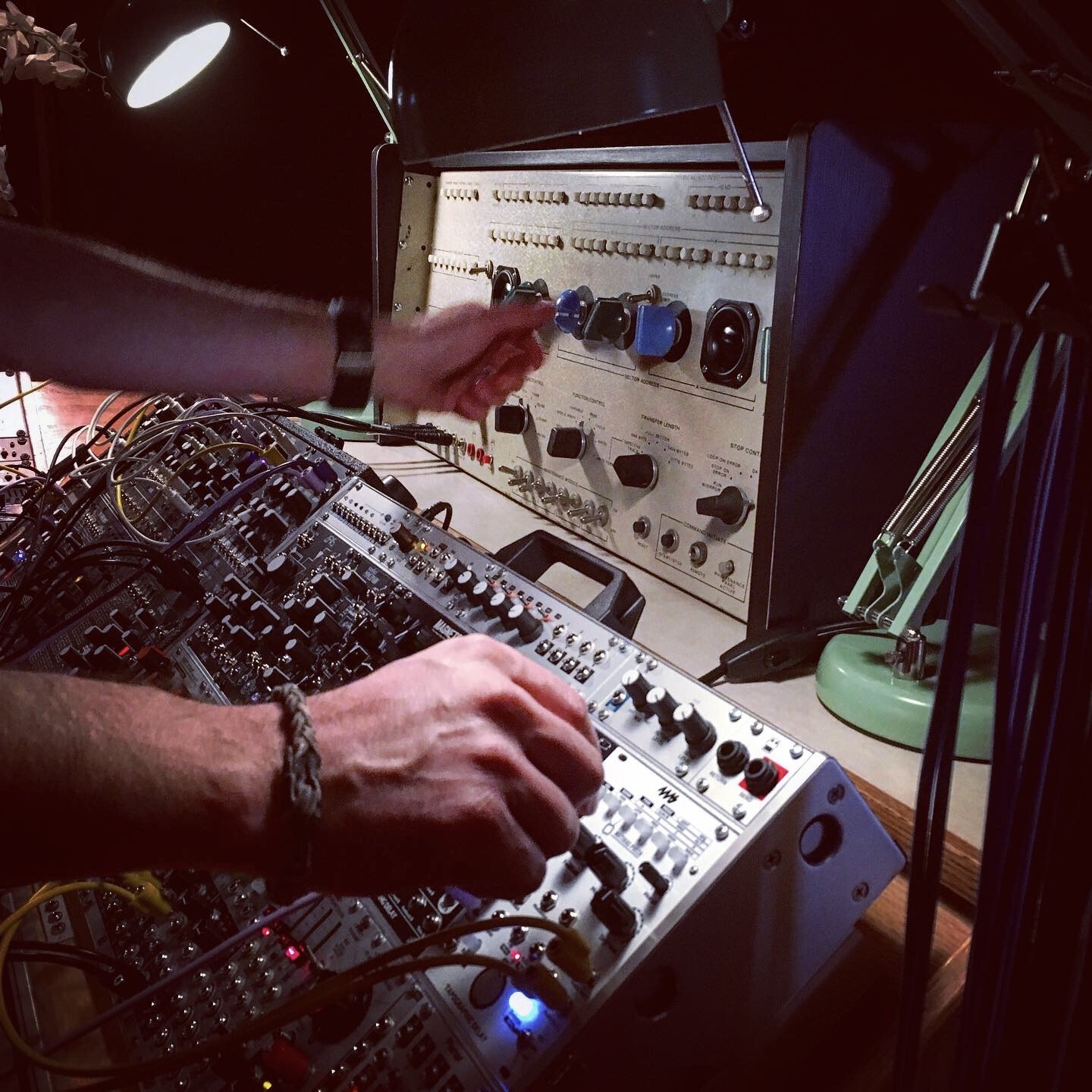 Close-up of hands playing a modular synth and custom device made from electronics salvage.