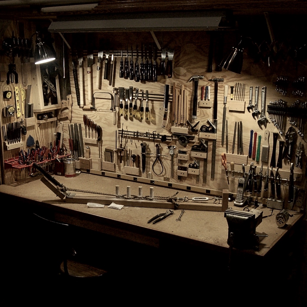 Wall-mounted hand tools above a wooden workbench.