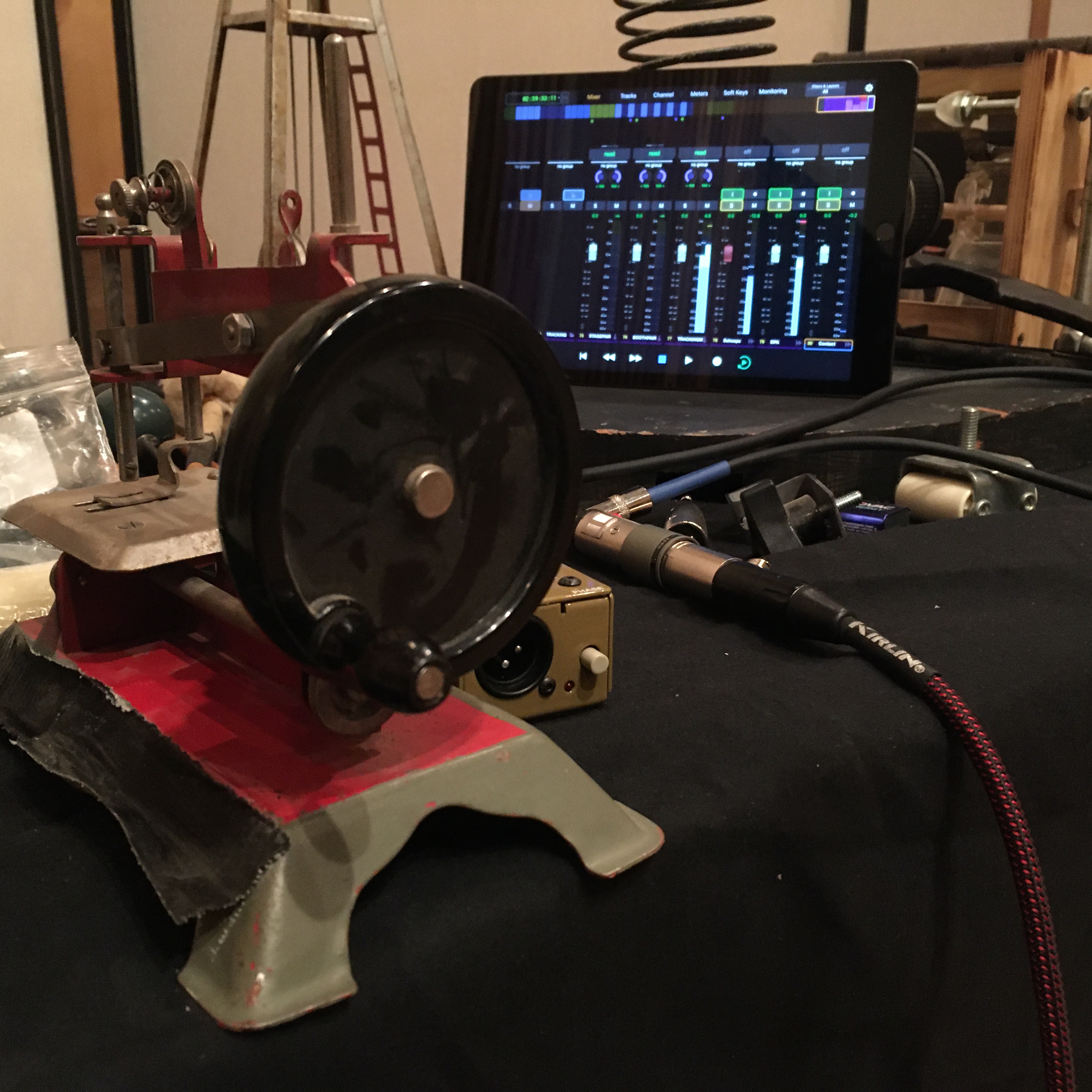 Close-up of a custom mechanical soundmaking device connected to audio recording equipment and a digital mixer.