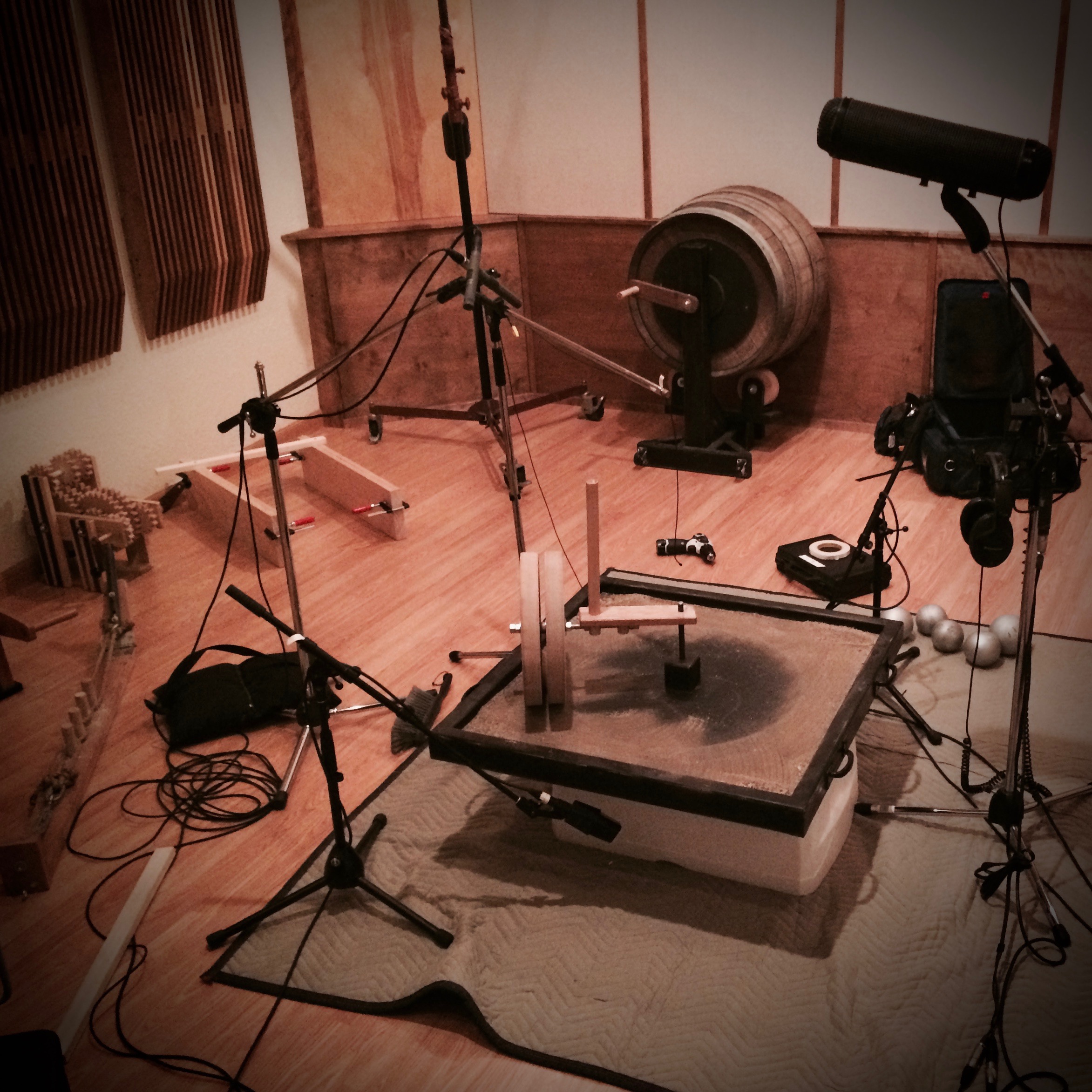 Sound recording setup with custom-built mechanical instruments, microphones, and stands arranged in a studio space.”